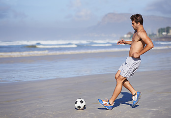 Image showing Man, beach and playing soccer for game, sports or exercise in outdoor hobby, training or practice. Young male person or football player with ball on ocean coast for match or cardio workout by seaside