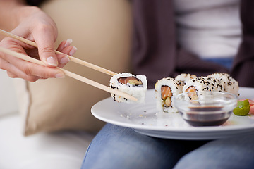 Image showing Hands, sushi plate and chopsticks in home, closeup or eating for wellness, diet or meal with soy sauce. Hungry person, fish and dish at lunch, nutrition or snack for takeaway food, house or apartment