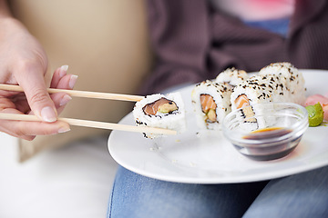 Image showing Hands, sushi plate and chopsticks in closeup, home or eating for wellness, diet or meal with soy sauce. Hungry person, fish and dish at lunch, nutrition or snack for takeaway food, house or apartment