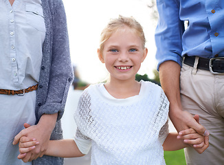 Image showing Portrait, holding hands and parents with child in garden for outdoor adventure, vacation or bonding. Relax, grass and family, happy girl with with mom and dad for summer fun with smile in backyard.