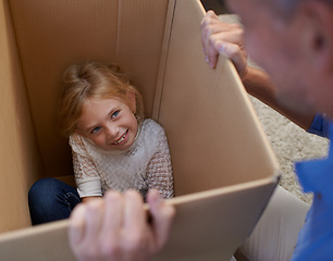 Image showing Moving, playing and girl in box with dad, fun in new home and happy package in apartment. Smile, father and playful child in cardboard with games, hiding and property investment for future family.