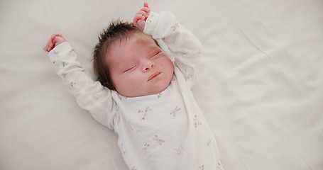 Image showing Newborn, face or sleeping with stretching on bed in nursery for relaxing or resting with child development. Baby, tired or dreaming in bedroom of house with calm, relax and cute infant in family home