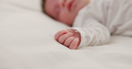 Image showing Hand, newborn and sleeping on bed in nursery with relaxing, resting and nap on blanket in morning. Baby, peaceful and dreaming in bedroom of home for child development, growth and nurture or relax