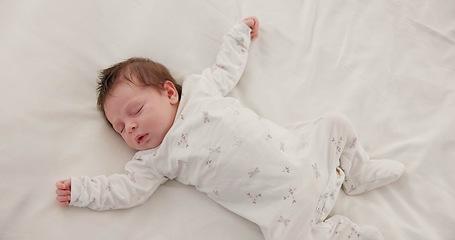 Image showing Sweet, sleeping and newborn baby on a bed at a home in the bedroom for resting and dreaming. Cute, tired and top view of infant, child or kid taking a nap in the morning in nursery at family house.