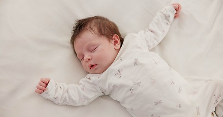 Image showing Cute, sleeping and newborn baby on a bed at a home in the bedroom for resting and dreaming. Tired, sweet and top view of infant, child or kid taking a nap in the morning in nursery at family house.