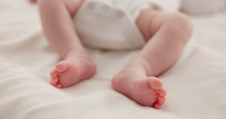 Image showing Sleeping, adorable and feet of baby on bed for child care, dreaming and relax in nursery. Family, cute and closeup of toes of innocent newborn infant for health, wellness and development at home