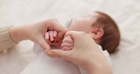 Image showing Bed, holding hands and mother with baby, love and support for care, health and wellness at home. Fingers, family or mama with a healthy infant, protection and child development with bond or maternity