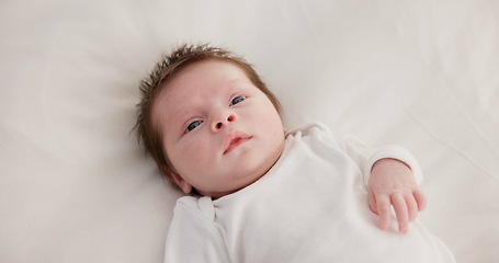 Image showing Baby, calm face and above in the morning on nursery bed and blanket awake from nap and rest. Relax and newborn with happy smile on bedding from waking up from sleeping in a family home and bedroom