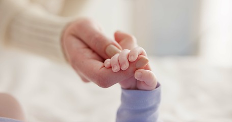 Image showing Sleeping, family and holding hands with baby on bed for bonding, love and relationship with infant. Adorable, care and closeup of parent with newborn for support, dreaming and protection at home