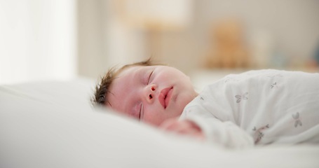 Image showing Tired, sleeping and newborn baby on a bed at a home in the bedroom for resting and dreaming. Cute, sweet and little infant, child or kid taking a nap in the morning in the nursery at family house.
