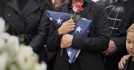 Image showing Funeral, graveyard and woman with American flag for veteran for respect, ceremony and memorial service. Family, depression and sad people with flower in cemetery for military, army and soldier hero