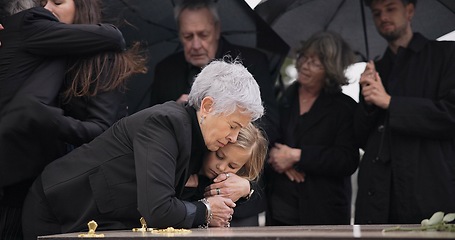 Image showing Funeral, crying family and child hug grandmother for support, mourning depression and death at emotional burial event. Dead, love and kid hugging senior woman, grandma and grief at farewell ceremony