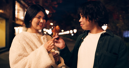 Image showing Women, friends and eating street food or travel Japan for night snack, experience or dessert. Female people, sidewalk and sweet donut on vacation for nutrition or culture, adventure or traditional