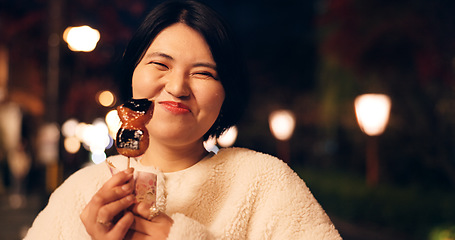 Image showing Woman, street food and eating Japanese snack for tourist experience, hungry or local. Female person, face and sidewalk at night for mochi candy for city vacation or culture, adventure or tradition