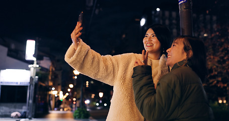Image showing Japanese, women and selfie outdoor at night with hand gesture, peace sign and happy in city street. Friends, people and phone with smile for travel, adventure and social media update in urban town