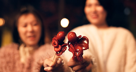 Image showing Women, Japan and travel street food at night for octopus delicacy, culture or traditional. Female people, snack and stick for tourism eating experience or cuisine in town for taste, dinner or holiday