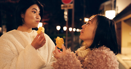 Image showing Woman, friends and street food or eating Japanese snack for travel experience, hungry or local trip. Female people, sidewalk and night walk on vacation for nutrition culture, adventure or traditional