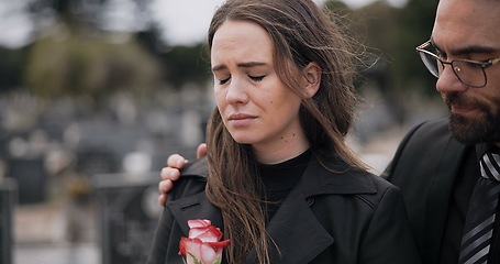 Image showing Support, death or couple in cemetery for funeral. spiritual service or burial to repsect the Christian religion. Rose, depressed or sad people hug for comfort in graveyard for grief, loss or mourning