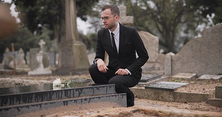 Image showing Funeral, cemetery and man with flower at tombstone for remembrance, burial ceremony and memorial service. Depression, death and person with rose for mourning, grief and loss in graveyard for respect