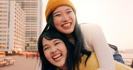 Image showing Friends, women and piggyback outdoor on promenade with bonding, laughing and adventure on holiday or vacation. Travel, Japanese people or embrace at beach in city with fun, comedy or freedom together