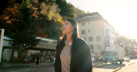 Image showing Japanese woman, walking and thinking in city, street and sunshine with vision, ideas or vacation. Girl, person and outdoor on metro sidewalk, road or happy for vacation, adventure or journey in Tokyo