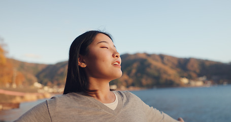 Image showing Japanese woman, freedom and peace outdoor, lake or ocean with travel, holiday and mindfulness in nature. Wellness, adventure and care free at beach in Japan, happy with breathing and positivity