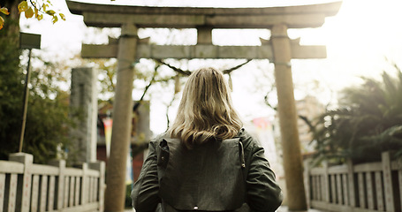 Image showing Woman, nature and torii gate in Kyoto with backpack, tourist and back with traditional history. Architecture, japanese culture and shinto shrine in woods with sculpture, memorial and monument