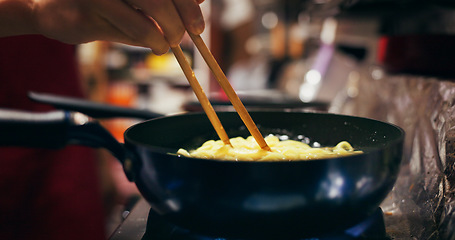 Image showing Cooking, restaurant and person with noodles in pan on gas stove at market for meal preparation, eating and cuisine. Culinary, flame and closeup of chopsticks to prepare lunch, dinner and supper