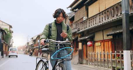 Image showing Bicycle, cellphone and man riding by building for exercise or transportation to college academy. Fitness, phone and young male student driving a bike to university for carbon footprint by houses.