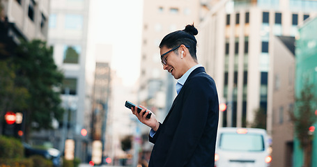 Image showing Cellphone, networking and Japanese businessman in city reading company email on technology. Career, travel and professional young male person scroll or browse on a phone with earbuds in urban town.