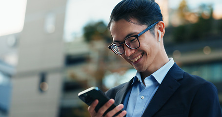 Image showing Phone, smile and Japanese businessman in the city reading company email on technology. Happy, career and professional young male person scroll or browse on cellphone with earbuds in urban town.