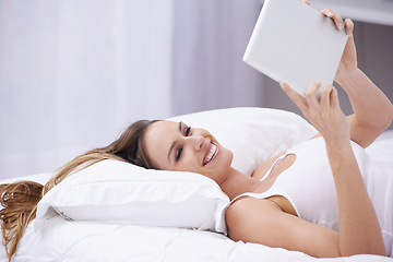 Image showing Happy woman, bed and relax with tablet for social media, communication or networking at home. Female person smile lying in bedroom on pillow with technology for online streaming or entertainment