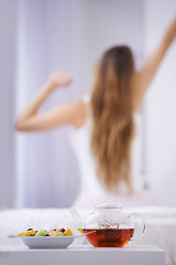 Image showing Breakfast, tea and woman in bedroom, stretching with fruit salad for good diet and nutrition. Healthy food, herbal drink and wake up, girl on bed getting ready to start day in home or hotel from back