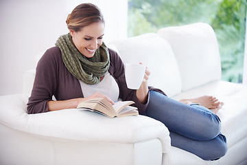 Image showing Happy woman, book and reading with coffee on sofa for story, novel or knowledge in living room at home. Lady, fiction books and drinking cup of tea for literature, hobby or comfortable break on couch