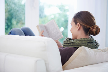 Image showing Woman, book and reading in home from the back for story, novel and learning knowledge on sofa in living room. Lady, fiction books and relax on couch with literature, hobby and comfortable in lounge