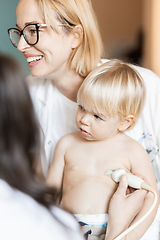 Image showing Small child being checked for heart murmur by heart ultrasound exam by cardiologist as part of regular medical checkout at pediatrician.