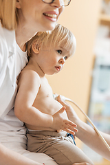 Image showing Small child being checked for heart murmur by heart ultrasound exam by cardiologist as part of regular medical checkout at pediatrician.