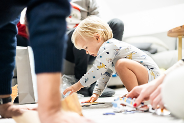 Image showing Parents playing games with child. Little toddler doing puzzle. Infant baby boy learns to solve problems and develops cognitive skills. Child development concept