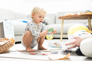 Image showing Parents playing games with child. Little toddler doing puzzle. Infant baby boy learns to solve problems and develops cognitive skills. Child development concept