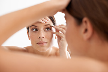 Image showing Beauty, mirror reflection and woman face for eyebrow maintenance, hair removal or cosmetic routine. Bathroom, tweezers and studio person grooming with facial plucking tools on white background