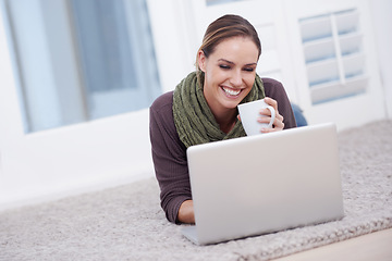 Image showing Woman, laptop and relax with coffee, happy with tech and streaming online for video or movie with internet at home. Connectivity, film or tv show, lying on carpet or floor for entertainment and drink