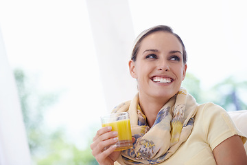 Image showing Woman, smile and drink orange juice from glass in home, thinking and memory with choice for detox on sofa. Person, fruit punch or liquid with ideas, relax and happy on lounge sofa in apartment