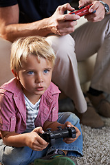 Image showing Family, serious and boy child gaming on floor in living room of home with father for love, competition or child development. Video game, controller for next level and son gamer playing with dad