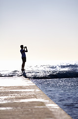 Image showing Silhouette, waves and ocean, man and photography with phone on holiday and travel in Miami, mockup space and summer. Adventure, content creator or influencer with picture for blog and sea view