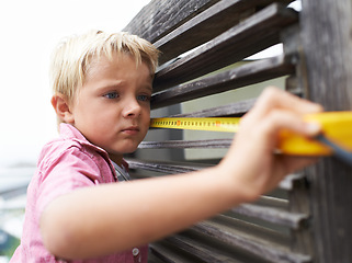 Image showing Focus, measuring tape and young child doing maintenance on wood gate for fun or learning. Serious, equipment and little boy kid working on repairs with tool for home improvement outdoor at house.
