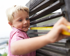 Image showing Smile, measuring tape and boy kid doing maintenance on wood gate for fun or learning. Happy, equipment and young child working on handyman repairs with tool for home improvement outdoor at house.