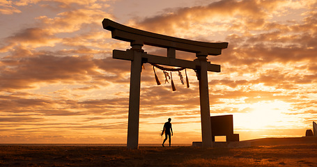 Image showing Torii gate, sunset sky and man at ocean with surfboard, spiritual history and travel adventure in Japan. Shinto architecture, Asian culture and calm beach in Japanese nature with sacred monument.