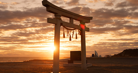 Image showing Torii gate, sunset sky and beach in Japan with clouds, zen and spiritual history on travel adventure. Shinto architecture, Asian culture and calm nature on Japanese landscape with sacred monument.