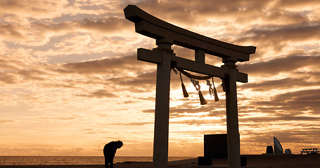 Image showing Torii gate, sunset sky in Japan and man in silhouette with clouds, zen and spiritual history on travel adventure. Shinto architecture, Asian night culture and calm nature on Japanese sacred monument.