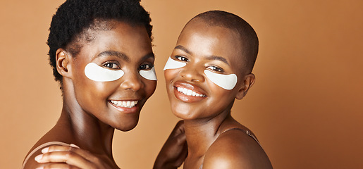 Image showing Beauty, eye pads and face of black women in studio with glowing, natural and facial routine. Smile, skincare and portrait of African female friends with cosmetic treatment by brown background.